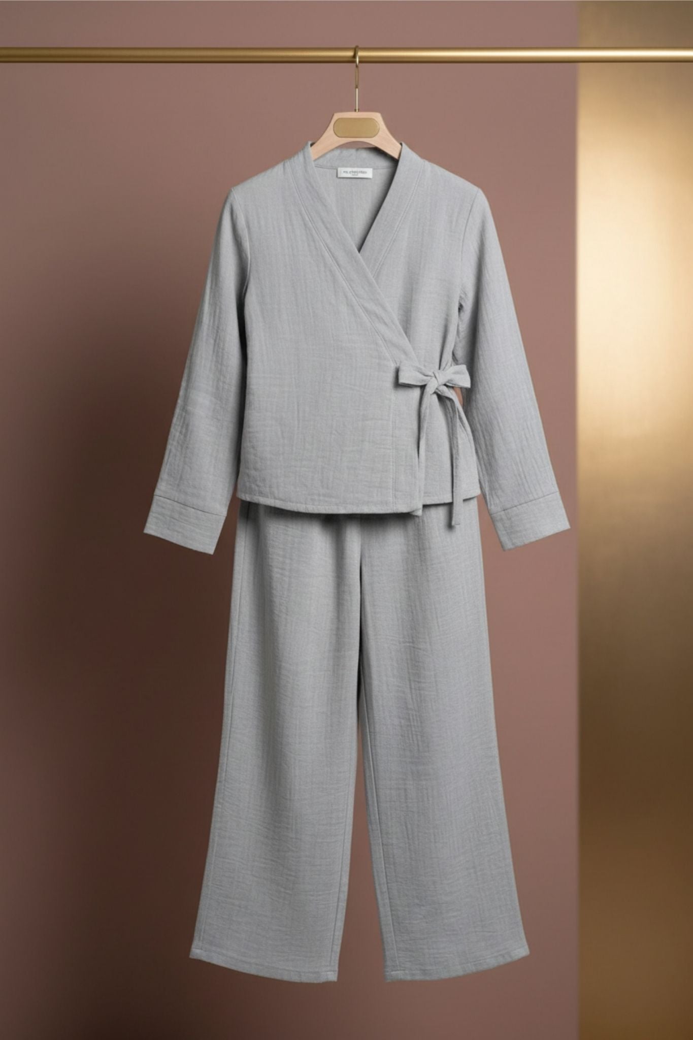 Grey robe and pants set on a hanger against a brown background