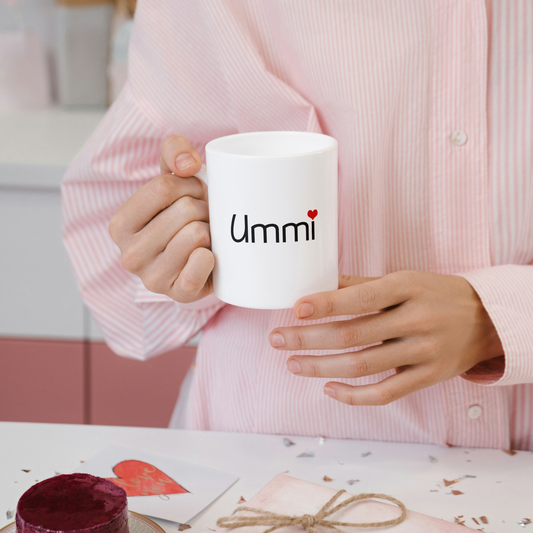 White ceramic mug with black “Ummi” text and red heart – styled on soft mint green blanket, Islamic gift for mom.