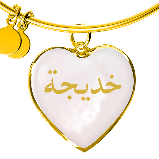 Gold heart bangle bracelet with Arabic name engraved on pink background, personalized Islamic jewelry