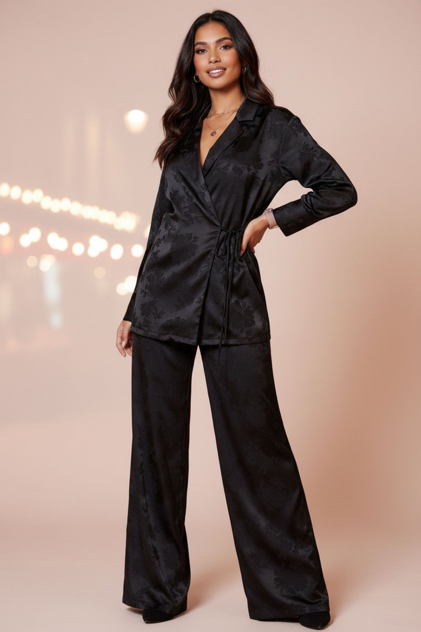 Woman wearing black satin wrap set with floral print - elegant blouse and wide-leg pants for special occasions