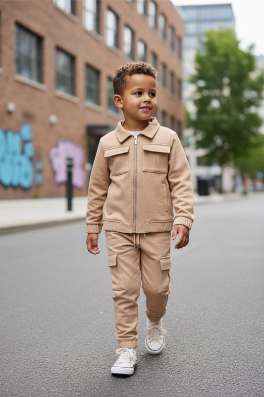 Child in a beige outfit walking on a street with buildings and trees in the background