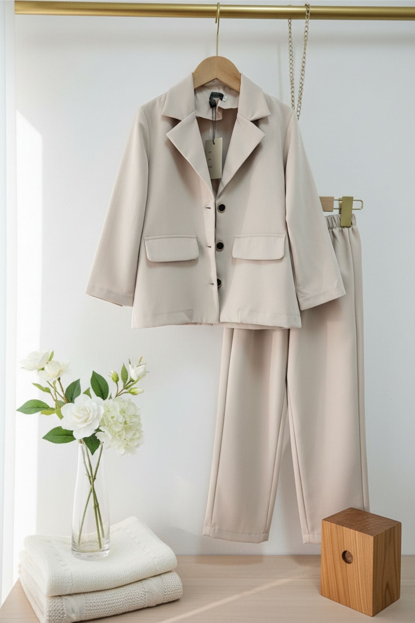 Beige suit on a hanger with a white wall background