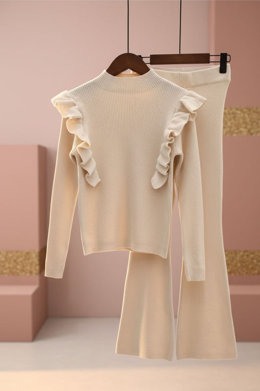 Beige outfit with ruffled details on a hanger against a pink wall.