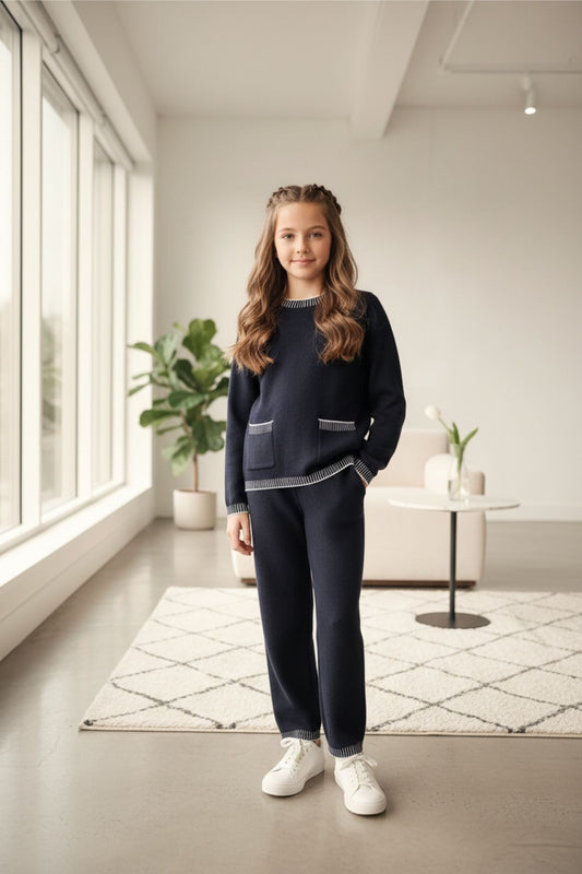 Young girl in a black knitset standing in a modern room with large windows and minimal decor.