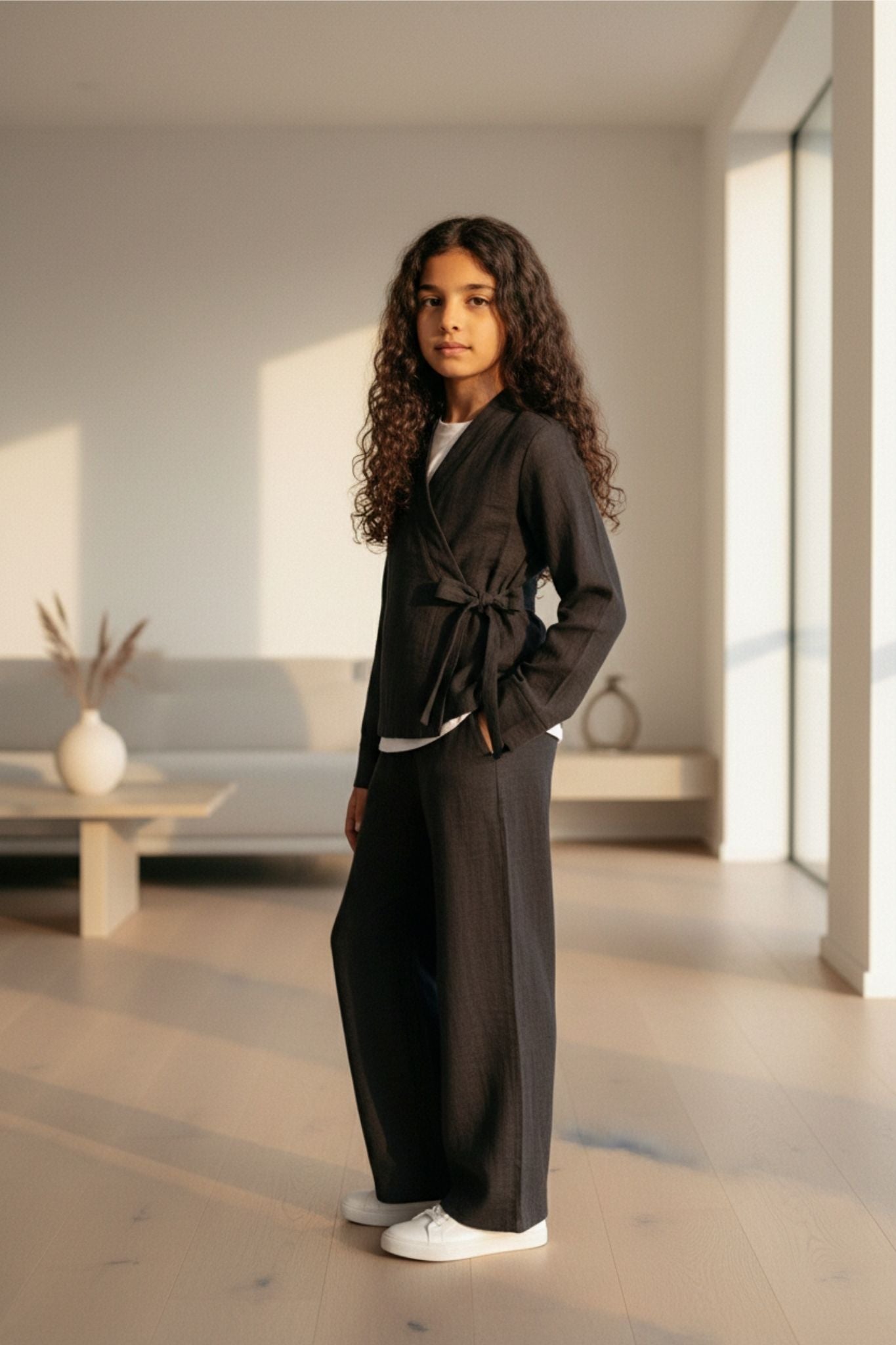 Girl in a black set standing in a modern room with large windows.