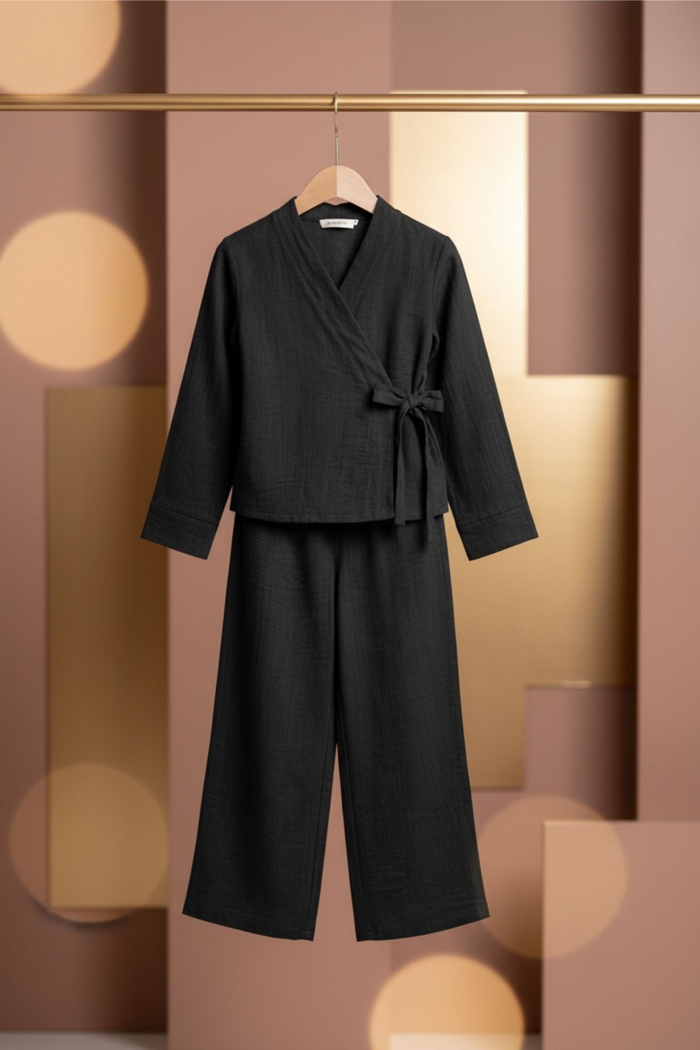 Black outfit with a jacket and pants on a hanger against a blurred background