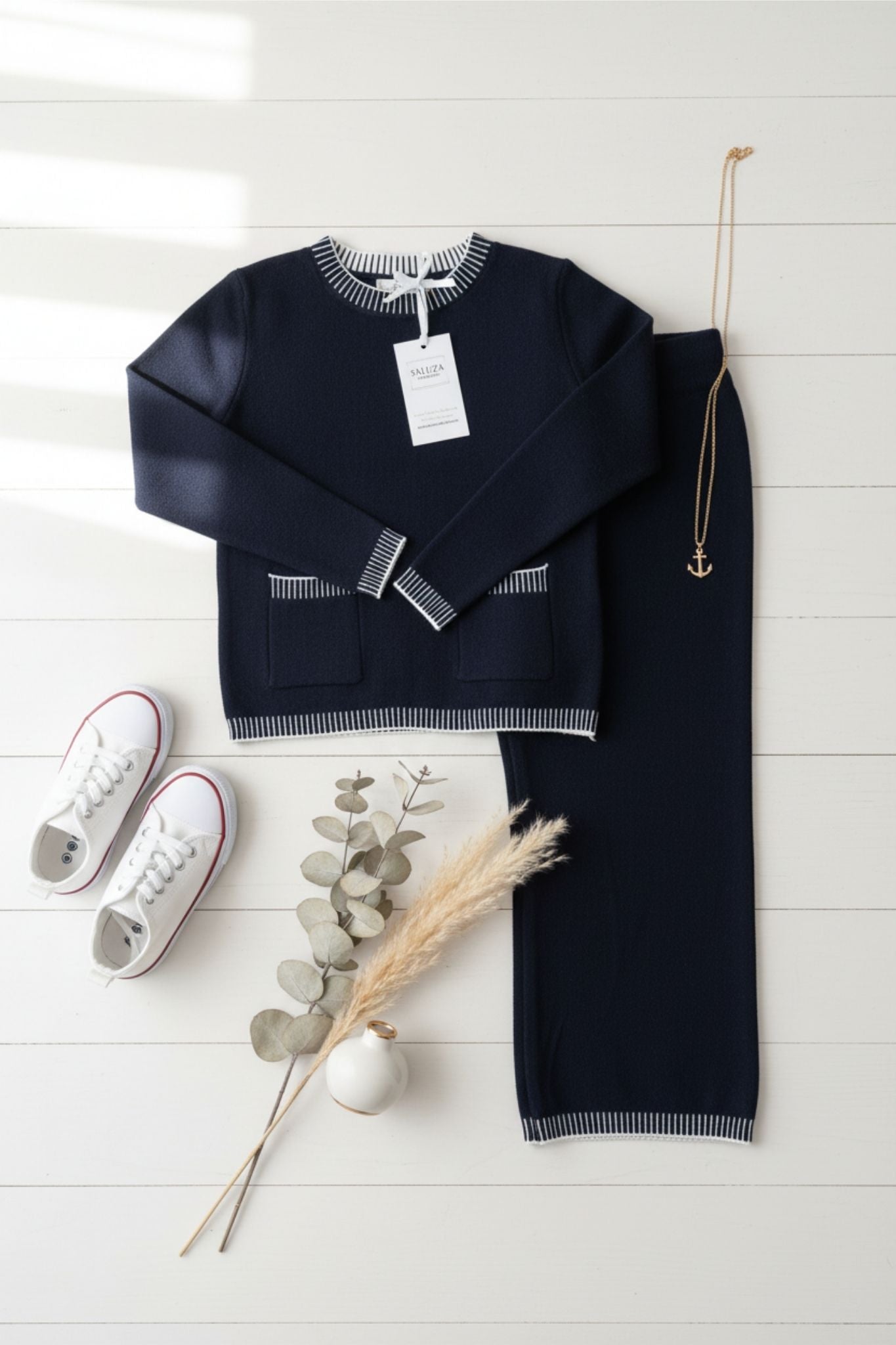 Black sweater and pants set with white sneakers on a light wooden floor