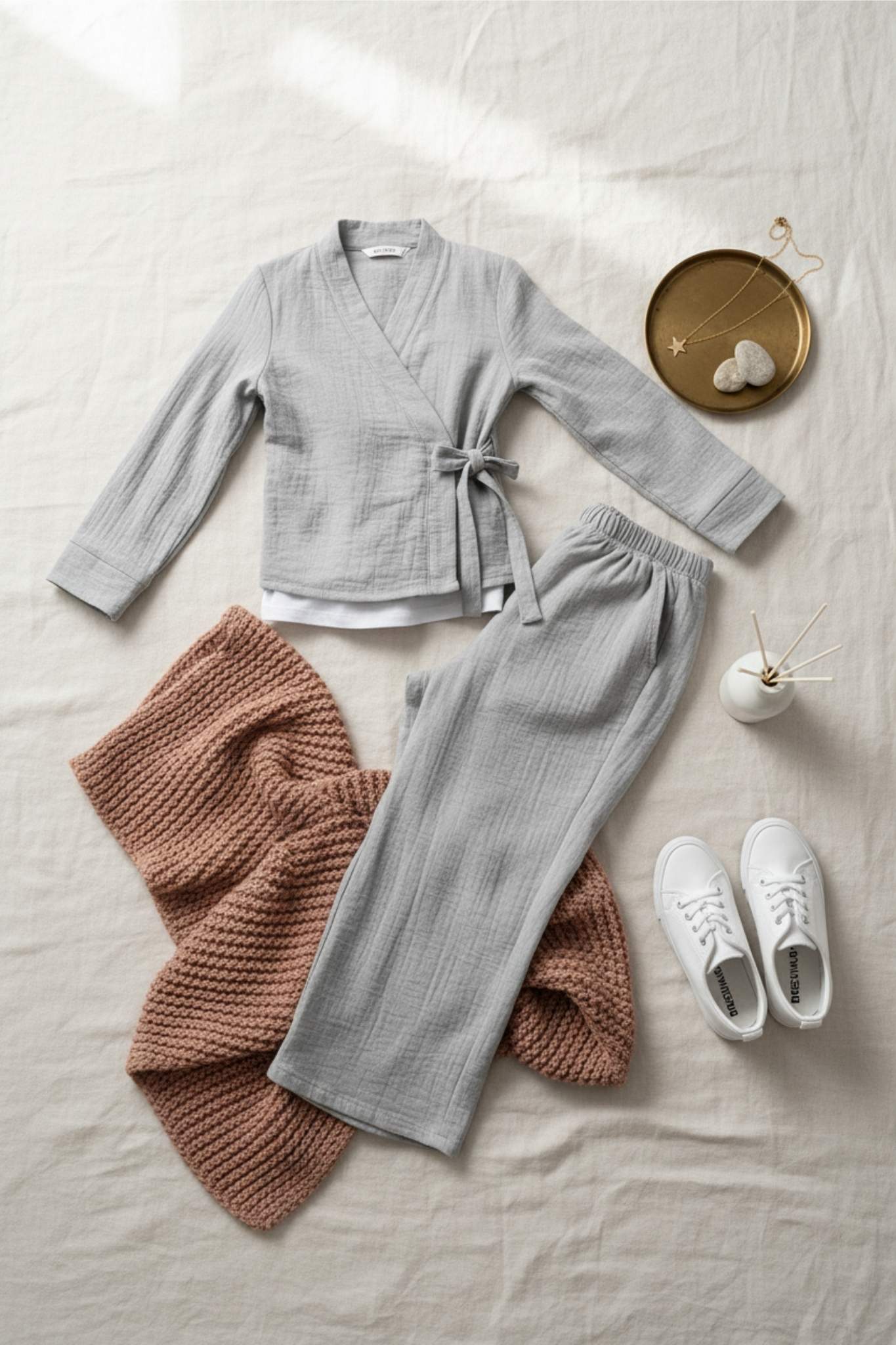 Gray robe, brown knitted blanket, gray pants, white sneakers on a light surface