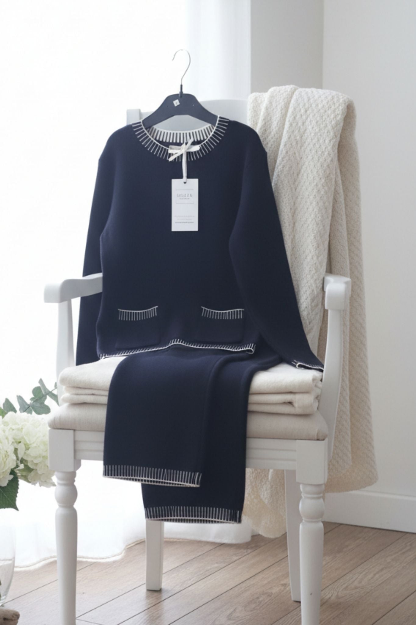 Black sweater with a tag on a white chair in a bright room
