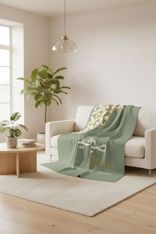 Sage green personalized blanket on modern sofa with pillows and warm home decor styling