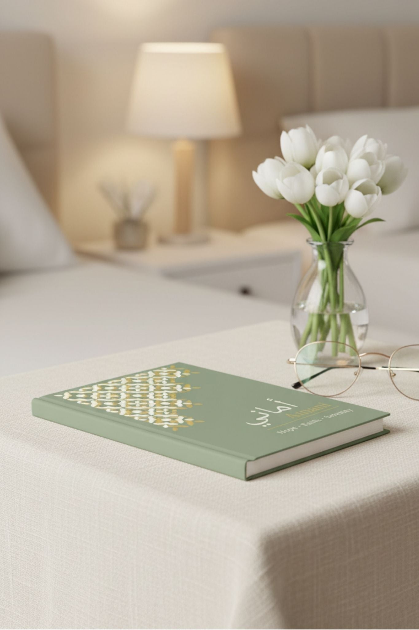 Sage green personalized journal on bedside table with flowers and elegant bedroom styling