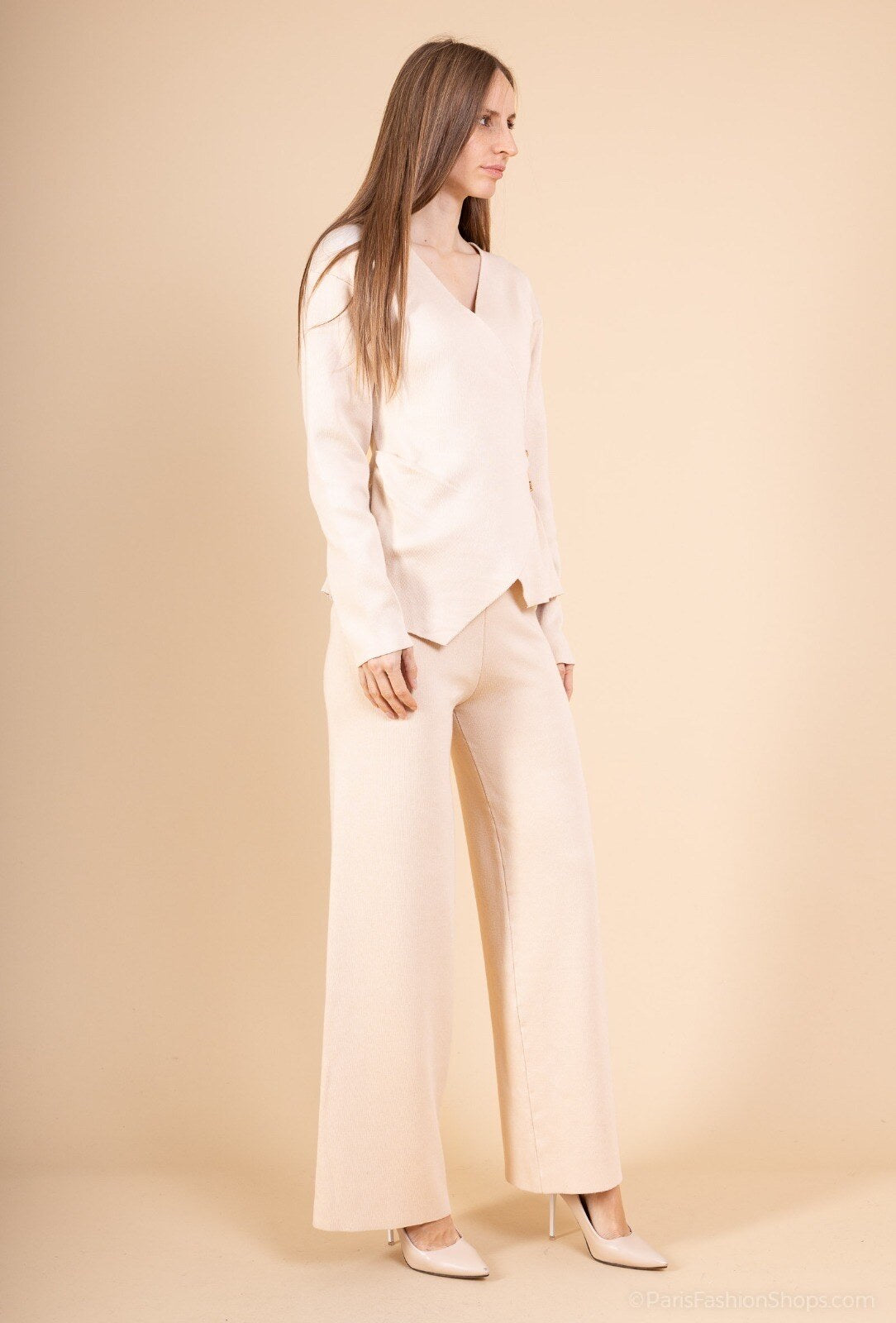 Woman wearing a light-colored outfit against a beige background