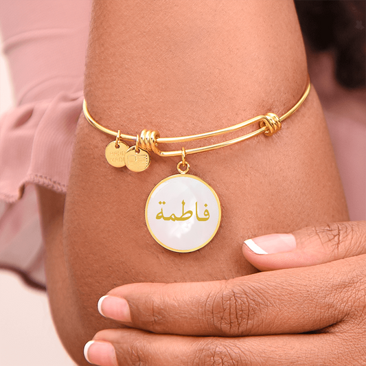 Round gold bracelet with Arabic name engraved in gold on a pink textured background – Islamic personalized jewelry for women