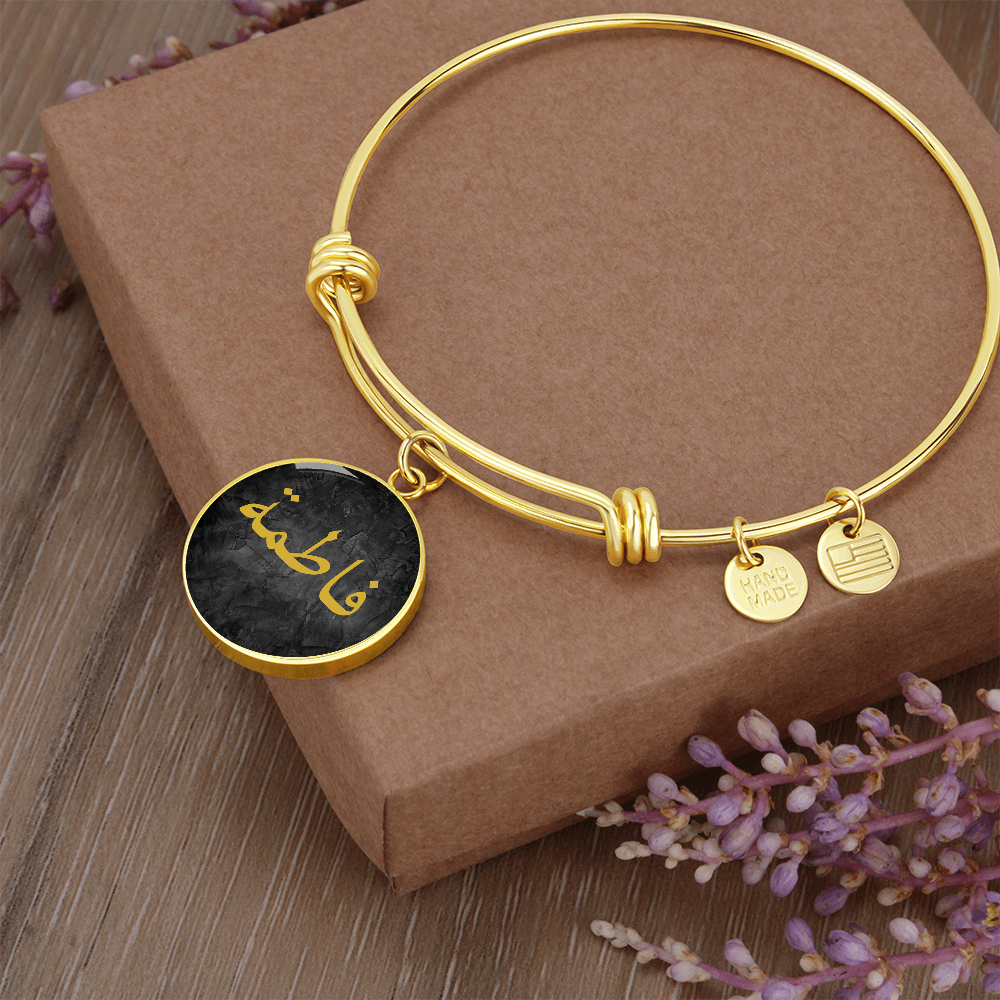 Round gold bracelet with Arabic name engraved in gold on a black textured background – Islamic personalized jewelry for women