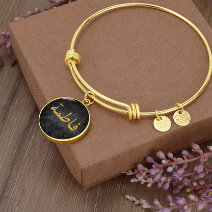 Round gold bracelet with Arabic name engraved in gold on a black textured background – Islamic personalized jewelry for women