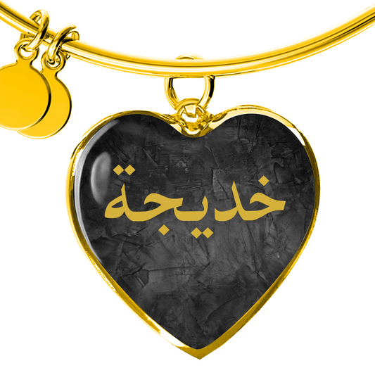 Gold heart bangle bracelet with Arabic name engraved on black background, personalized Islamic jewelry