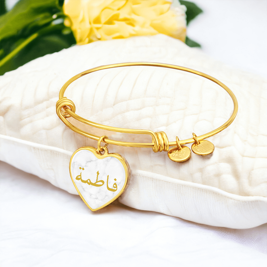 Gold heart bangle bracelet with Arabic name engraved on white background, personalized Islamic jewelry