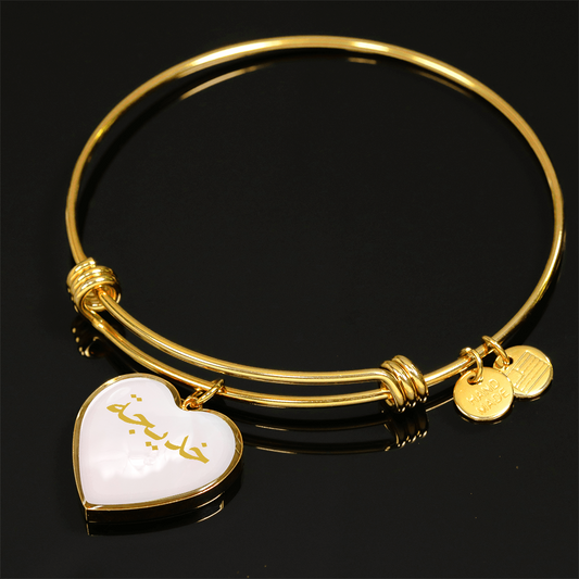 Gold heart bangle bracelet with Arabic name engraved on pink background, personalized Islamic jewelry